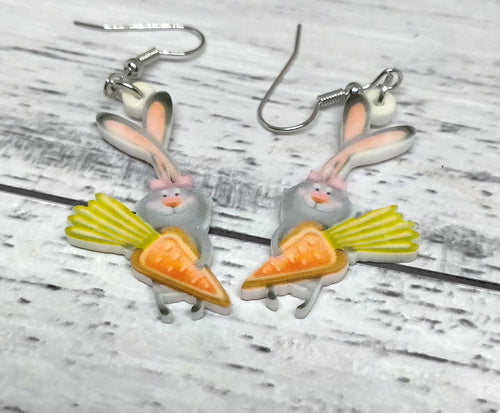 a pair of earrings with a rabbit holding a carrot